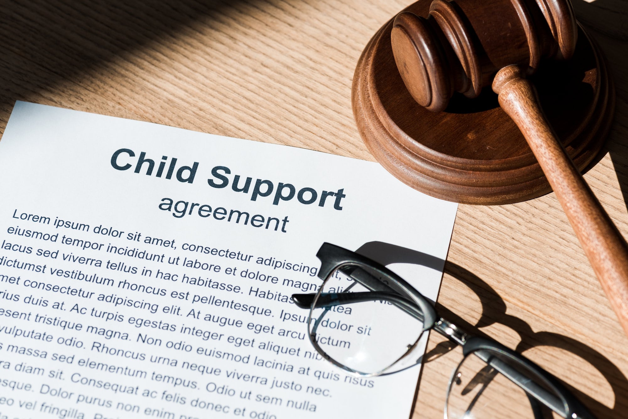 Legal document of child support agreement, with glasses, and a gavel and hammer